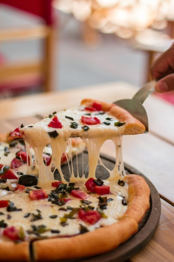 		A slice of pizza being lifted up with cheese falling from it
	