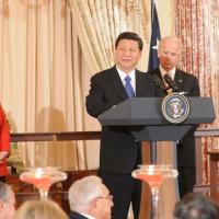 		Chinese President Xi Jinping standing at a podium with the US Seal on the front, with Joe Biden behind him and Hilary Clinton to his left dressed in a red pants suit.
	