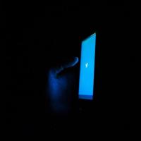 		Blue phone screen glows against a dark background
	