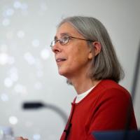 		Martha Haynes with glasses, shoulder-length gray hair in a red top, with blurred stars on screen behind her
	