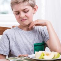		Child making a face at a cut up apple on a plate
	