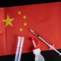 		Red flag (of China) with medical syringe and bottle on top of it
	