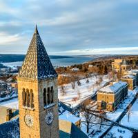 		Clock tower in foreground, snowy college campus in the distance, seen from above in low light
	