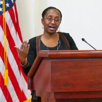 		Person speaking at a podium; American flag in the background
	