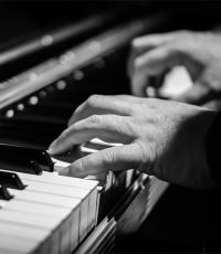 		 A black and white photo of two hands playing a piano
	