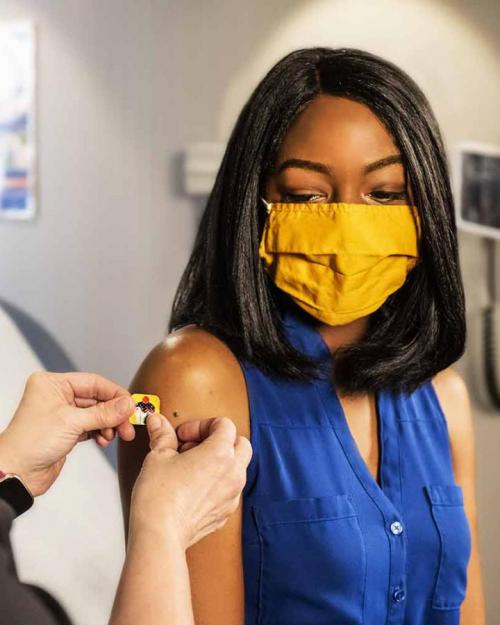 Person receiving a post-vaccine bandage from a medical worker
