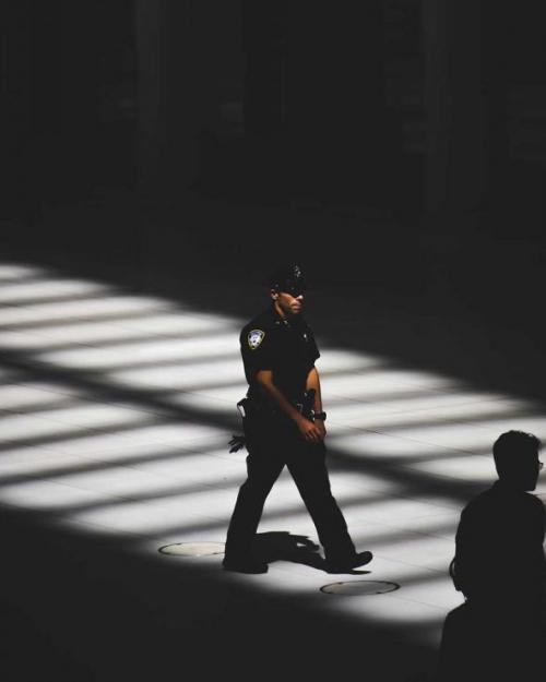 		person in polic uniform, walking through shadowy space
	