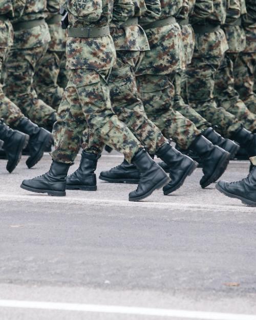 		Soldiers dressed in army camouflage march in formation 
	