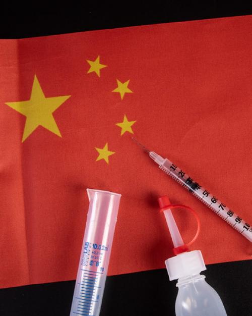 		Red flag (of China) with medical syringe and bottle on top of it
	