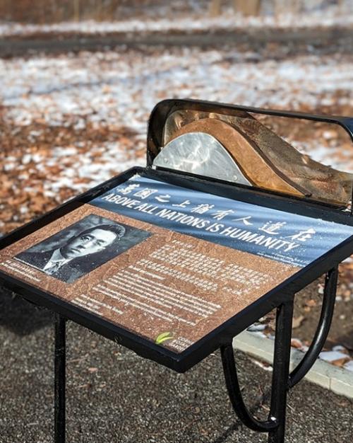In a natural areas, a stone bench is next to an interpretive sign