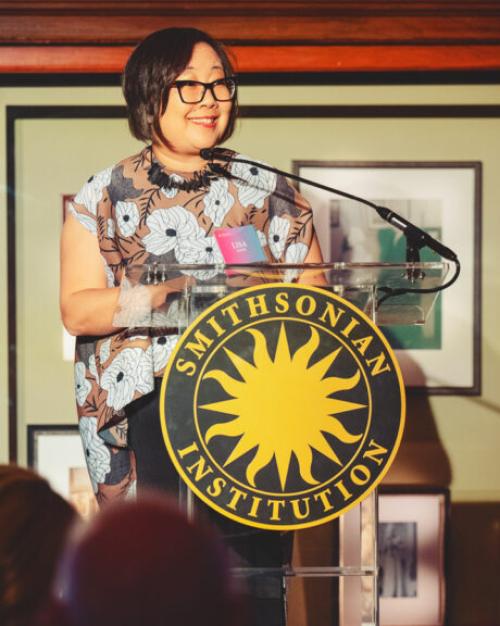 		Person standing at a podium with a &quot;Smithsonian Institution&quot; logo
	