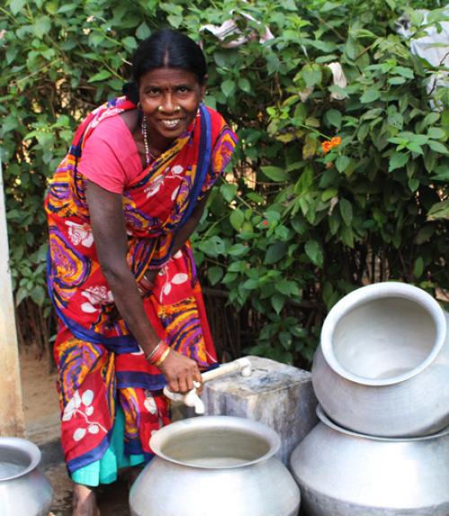 		 Woman in India cleaning out her water containers
	