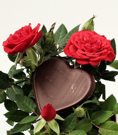 		 A heart shaped chocolate candy with two roses
	