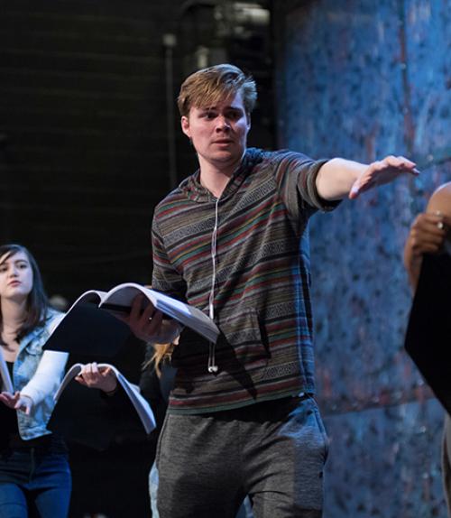 		 Student rehearsing a play on lit stage
	