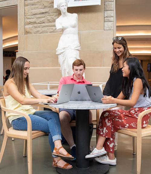  Members of Human to Human team with computers sitting around a table in the Temple of Zeus cafe