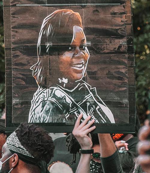 		 A poster with a drawing of Breonna Taylor carried aloft during a protest
	