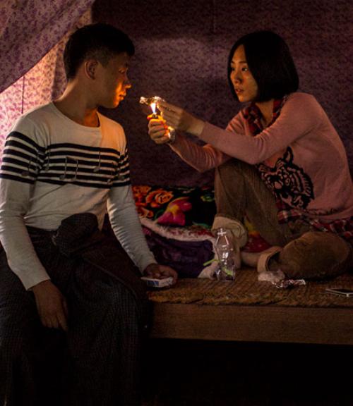  In an image from a Midi Z film, a woman offers a man a light for his cigarette