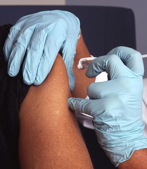 		 Gloved hands administer a shot to an upper arm
	
