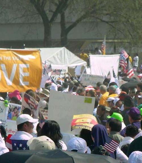 		 People at a rally holding American flags and signs
	