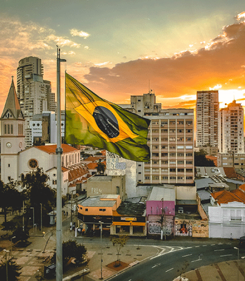 		 Brazilian flag with city and sunset in background
	