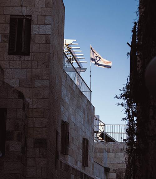  Sky and a flag show between dark buildings