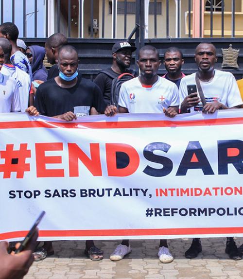  Several people stand behind a white banner with red and black lettering