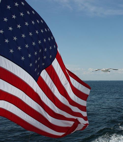 		 US Flag flying over the ocean
	