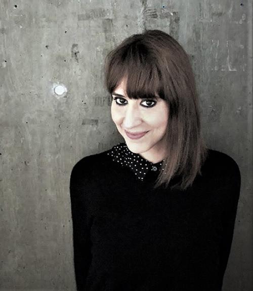 		 Valeria Dani - a woman in a black sweater before a gray, concrete background.
	