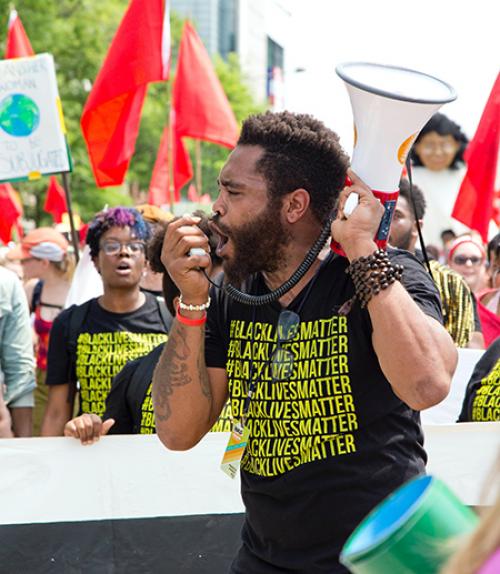  Person holding megaphone with crowd behind