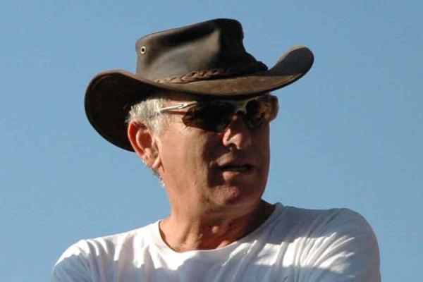 White-haired Aviam wearing a leather cowboy hat, wearing sunglasses and a white t-shirt.