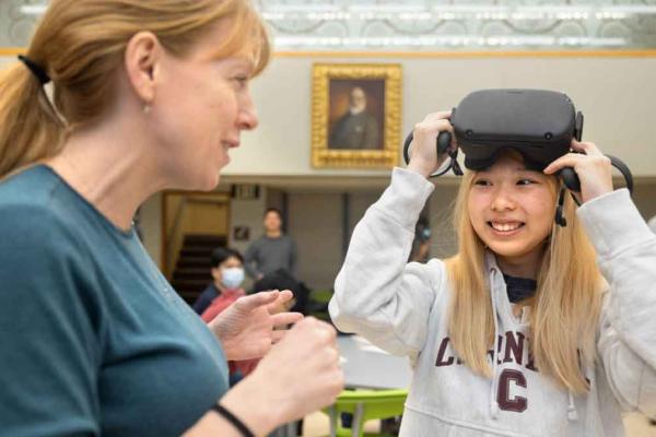 student with VR glasses and adult helping her