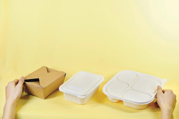 Three takeout food packages against a yellow background