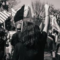 A woman standing with her fist upraised at a protest at the White House