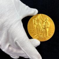 Gloved hand holding a gold medal