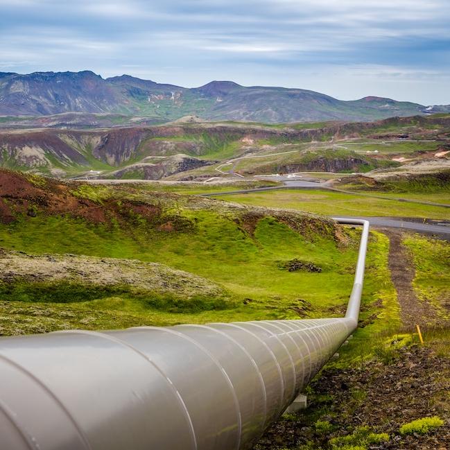 above-ground pipeline extends across a rugged landscape