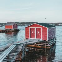 Two red shacks on log platforms in a bay