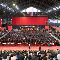 An auditorium with a large crowd celebrating a graduation