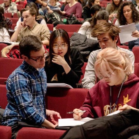 Four people confer over notes