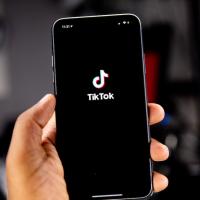 Hand holding a smart phone showing the TikTok icon