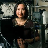 Michelle Wang, next to a microscope and with dangling wires and equipment behind her