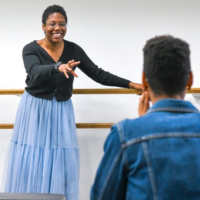 Person gesturing to two others: a theatre director at work