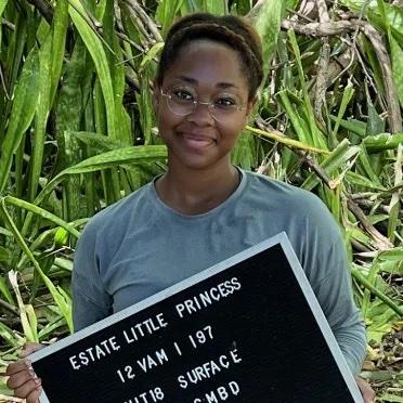 Person standing in a field holding a sign that says "Estate Little Princess"