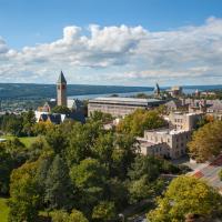 Cornell's central campus: stone buildings set among green trees with a blue sky above