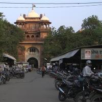 		A gold building foregrounded by rows of stalls and many parked motorcycles
	