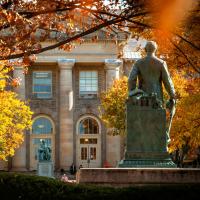 Statue facing a campus building; fall foliage
