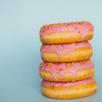 		Four donuts in a stack: frosted pink, covered with sprinkles
	
