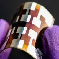 Gloved fingers hold tiny metal panel