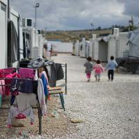 Three children walk away down a path between tents