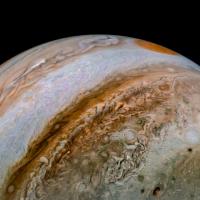 Jupiter with bands of swirling color and a red spot at top of sphere.