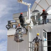 Three people in hard hats working with machinery outdoors